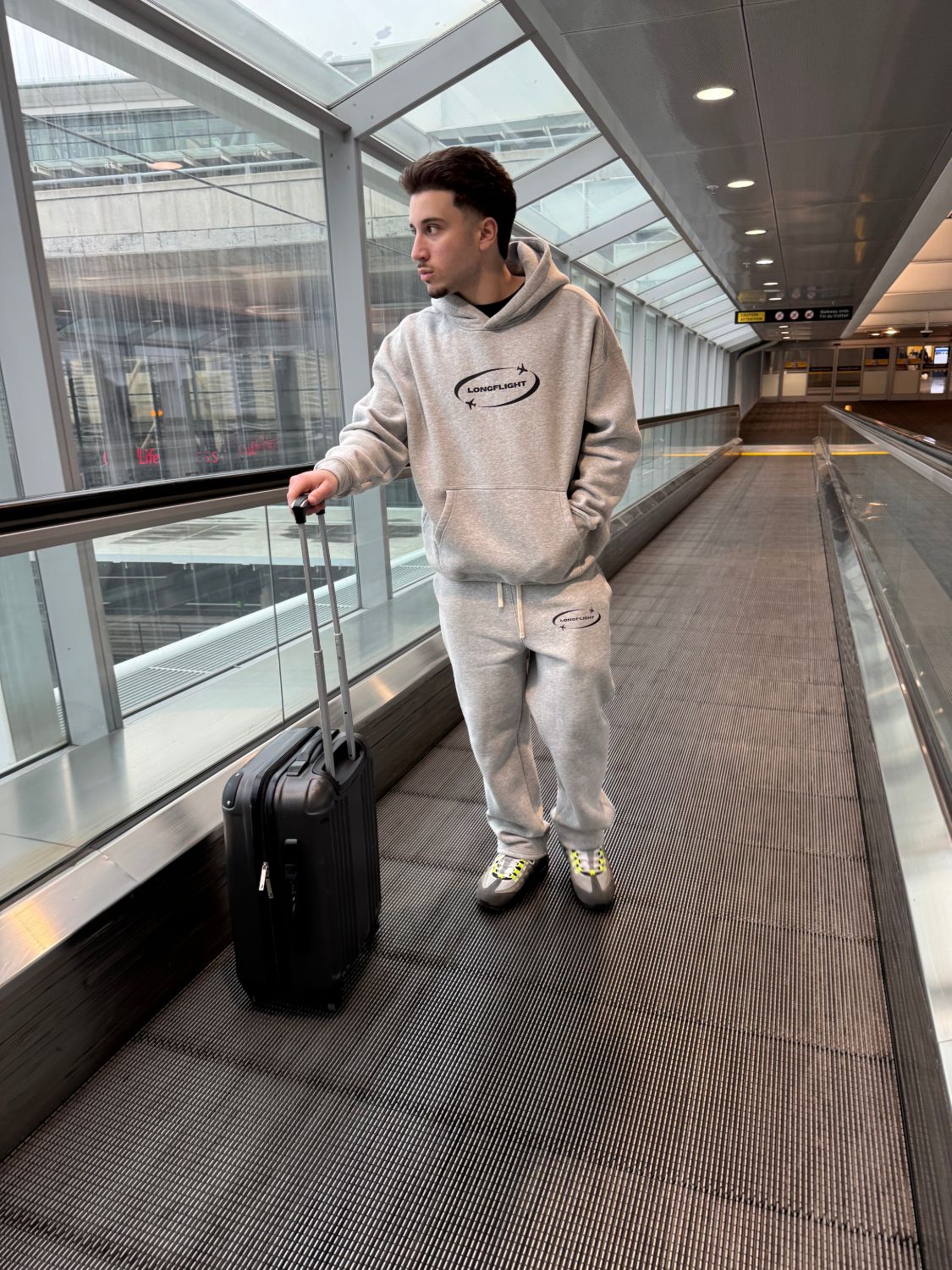 Model wearing the Signature Hoodie in heather grey at the airport, front view